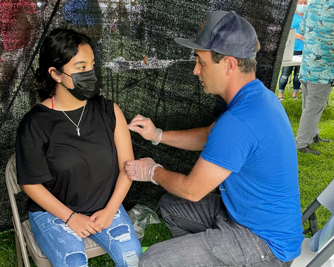 José Torradas rubs alcohol on a masked woman's arm