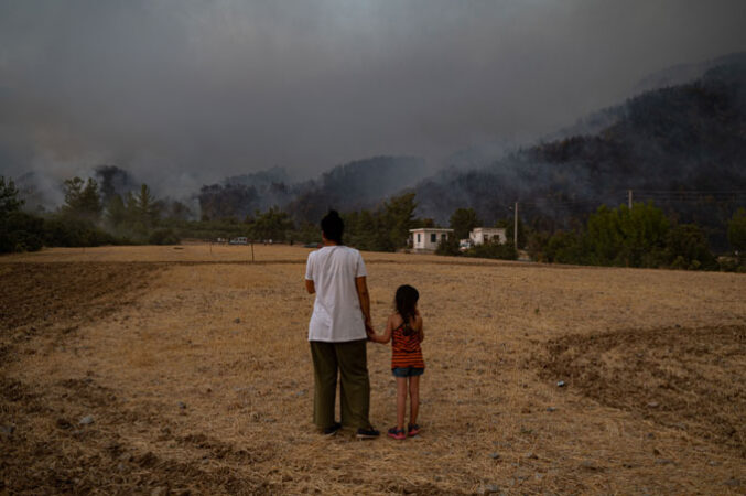 photo of a woman and a child looking at smoke from wildfires in the distance in Turkey